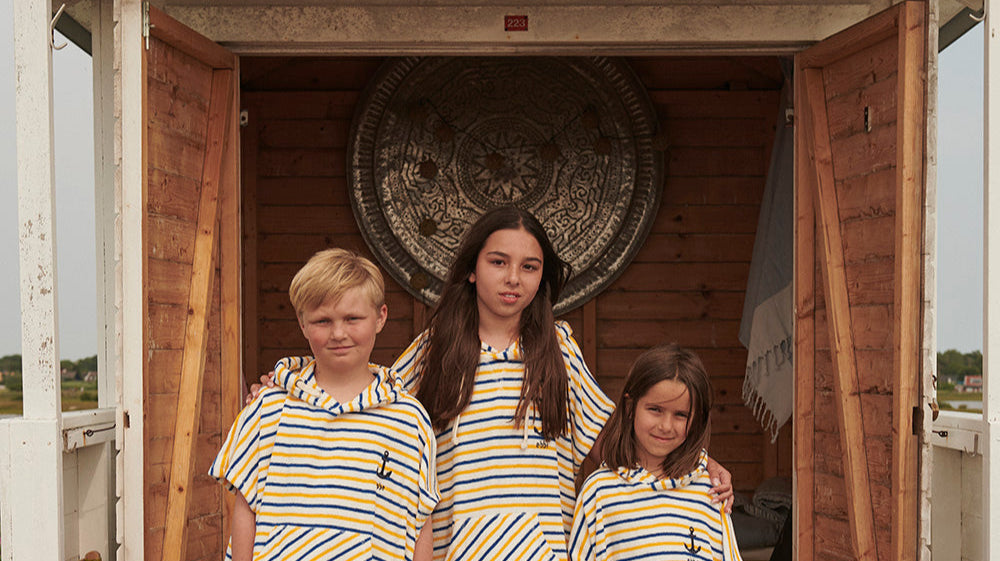 Barn i solskydd och badponcho vid badhuset