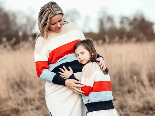 Mamma och dotter i randiga stickade tröjor på ett fält