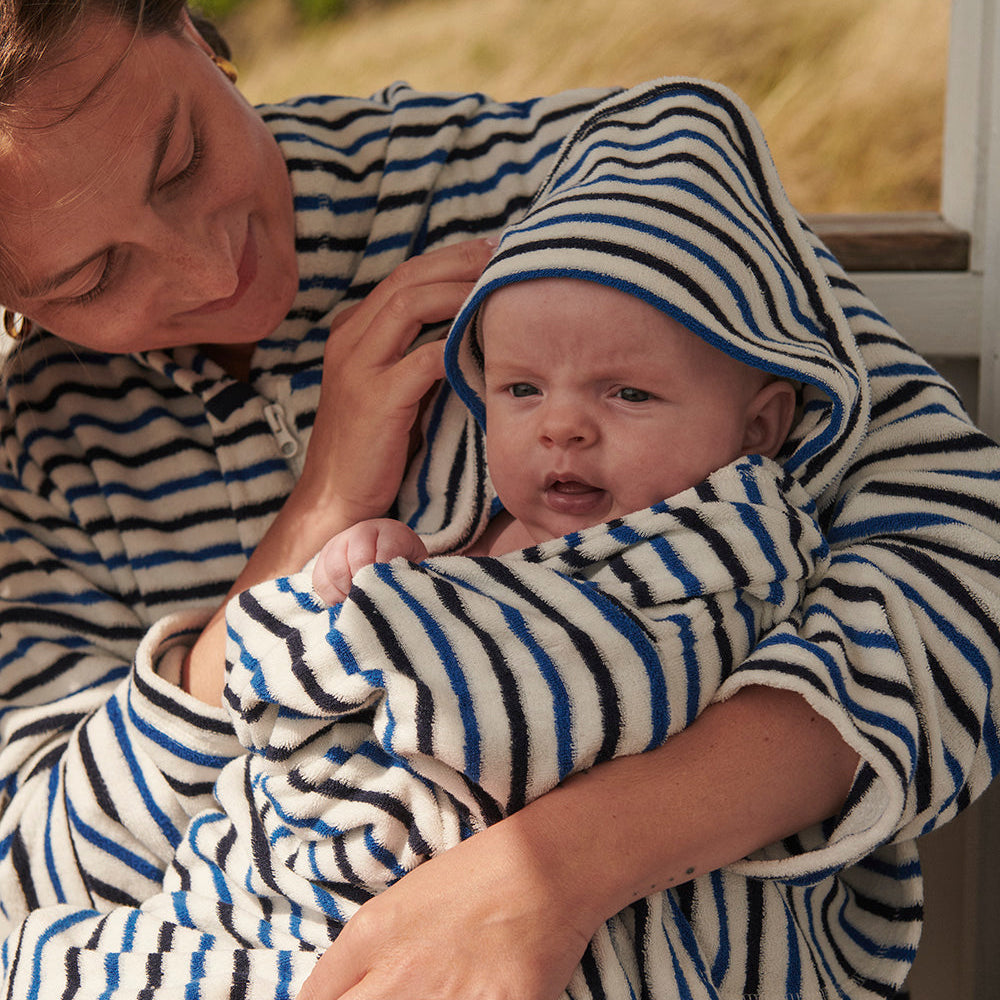 Nyfödd baby insvept i randig handduk med huva